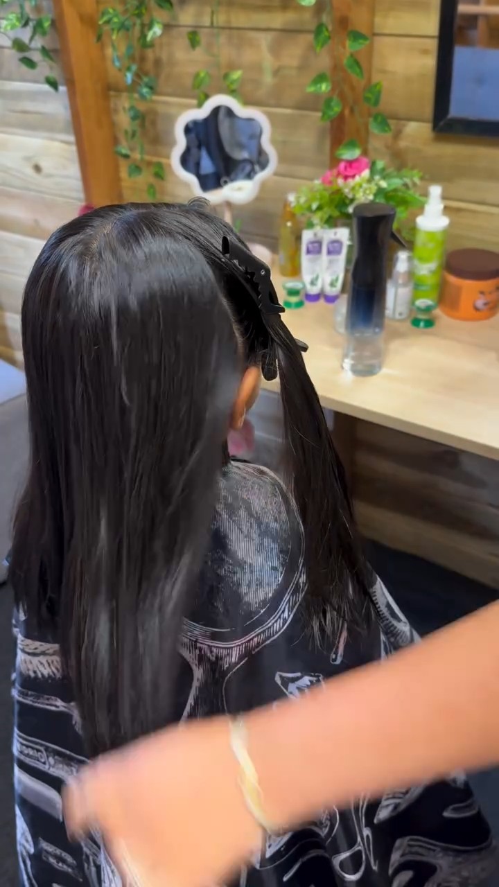 Knippen in de salon: lang zwart haar wordt gekamd en op lengte gebracht