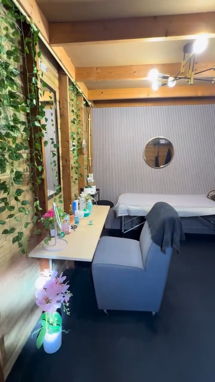 De hele salon: behandelbank, stoel, ronde spiegel en klimop langs de wand